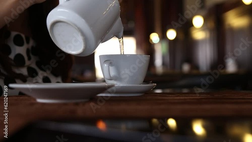 women pouring hot water on tea bag in a vintage dark cafe 