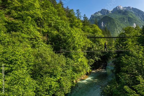 Active young man walking over suspension bridge in mountains