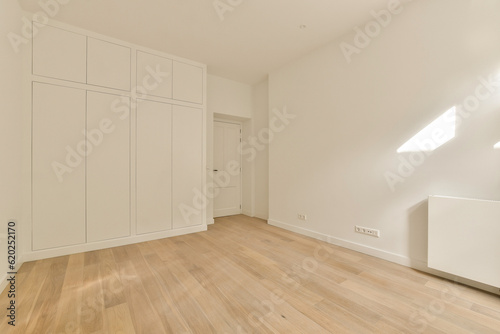 an empty room with wood floors and white cabinets on the wall to the right, there is no one door