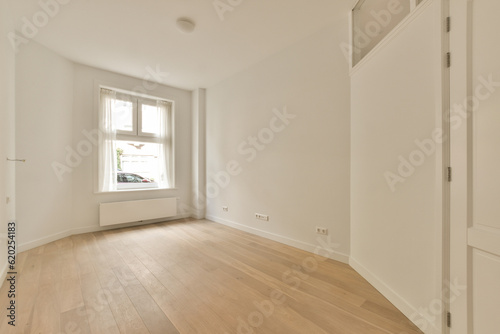 an empty room with wood flooring and white paint on the walls there is a large window in the corner