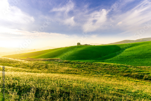 scenery rural view of a contryside farm in green fields and hills with amazing cloudy sky on background