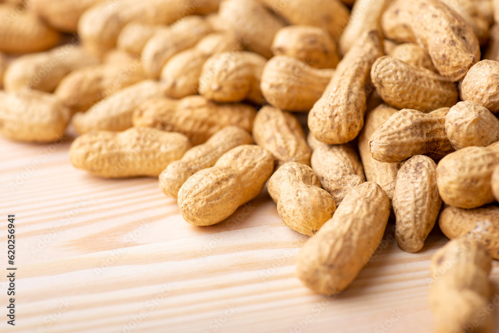 Some peanuts in shell on wooden table. Close up of unpeeled peanuts background Some peanuts in shell on wooden table. Close up of unpeeled peanuts background