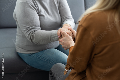 Fototapeta Naklejka Na Ścianę i Meble -  I know you can. Close up of millennial woman grown daughter, grandchild or younger friend holding tight hand of old mother, grandmother, elder relative or colleague helping to overpass life problems.