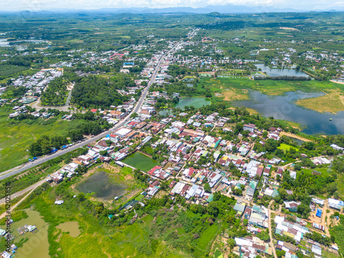 Aerial view of National Route 20 in Dong Nai province, group of floating house on La Nga river, Vietnam with hilly landscape and sparse population around the roads.