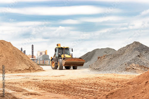 Powerful wheel loader or bulldozer at the construction site. Loader transports sand in a storage bucket. Powerful modern equipment for earthworks and bulk handling.