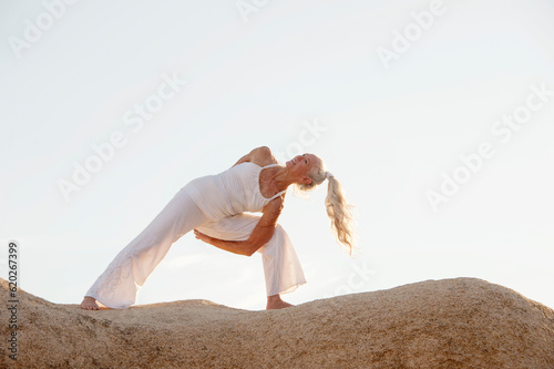 Senior woman yoga twist in nature. 