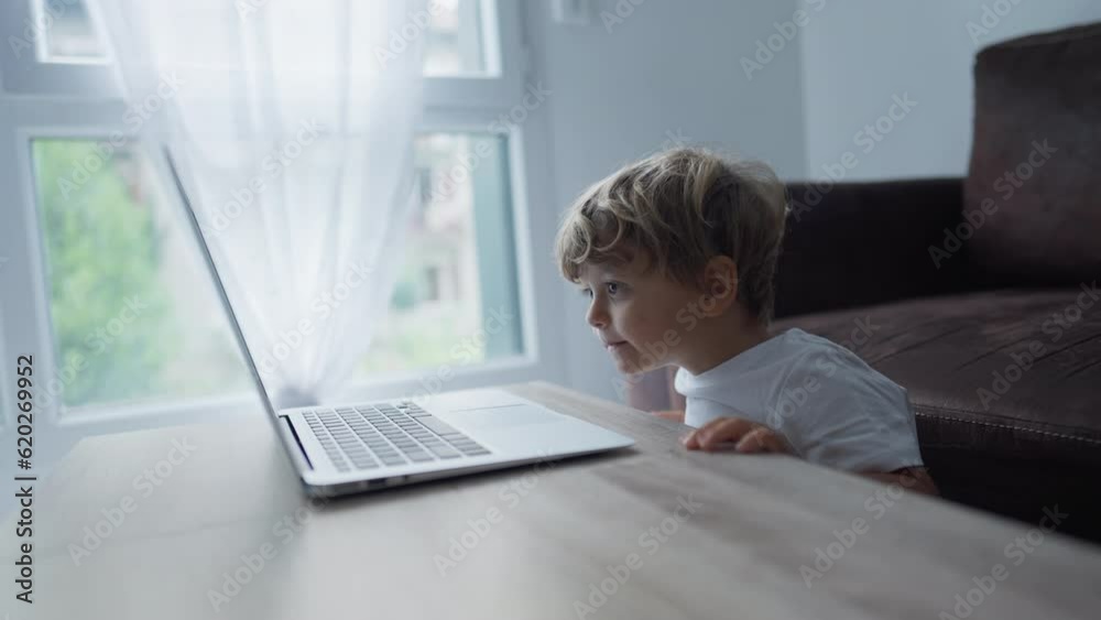 Child watching cartoons on laptop computer at home while eating apple fruit snack