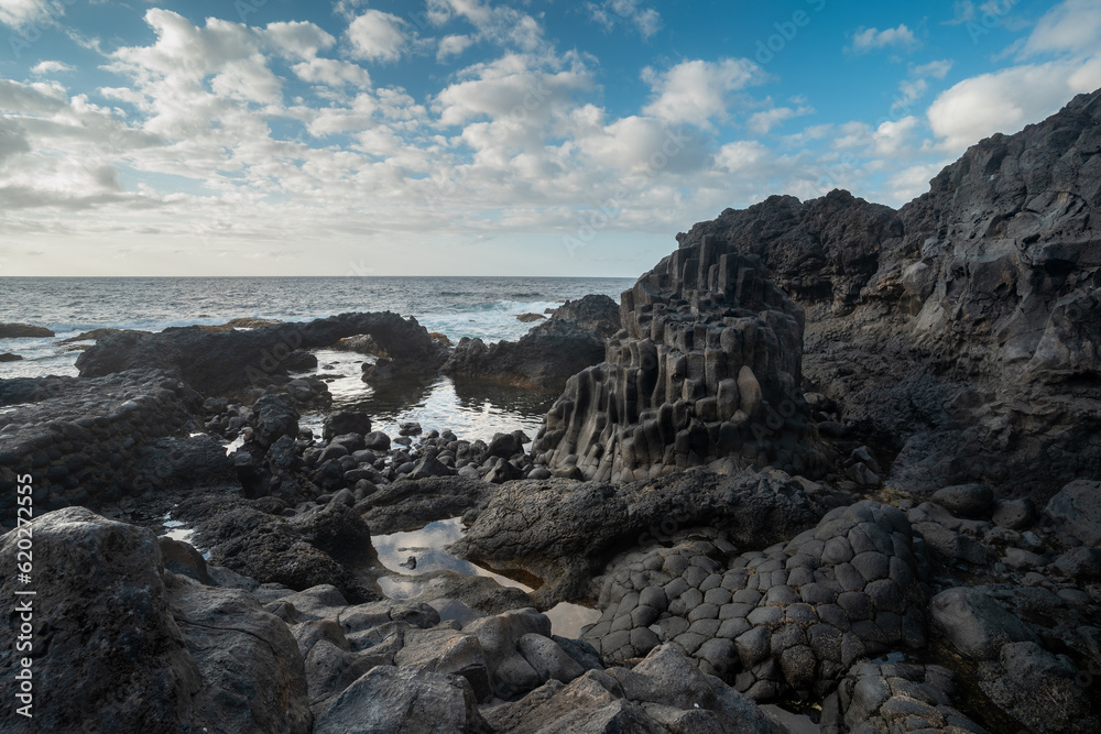 Long exposure. rocky beach with a natural arch with blue sky. Charco Azul. El Hierro island. Canary Islands	