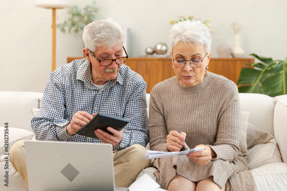 Middle aged senior couple sit with laptop and paper document. Older mature man woman reading paper bill pay online at home managing bank finances calculating taxes planning loan debt pension payment - obrazy, fototapety, plakaty 