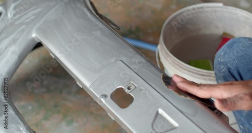 Polishing sandpaper with water to prepare the surface for further painting.
