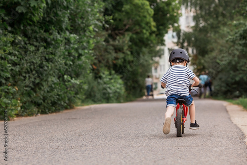 Wallpaper Mural A cheerful little boy rides a running bike in a helmet outdoors. A happy child is engaged in an active sport. Protection. Life insurance and child safety. Torontodigital.ca