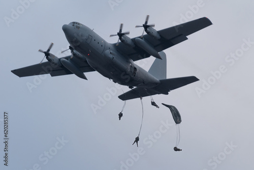 military logistic transport plane dropping paratroopers on a cloudy day at dawn