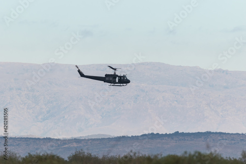 Military transport helicopter in flight with colorful mountains in the background