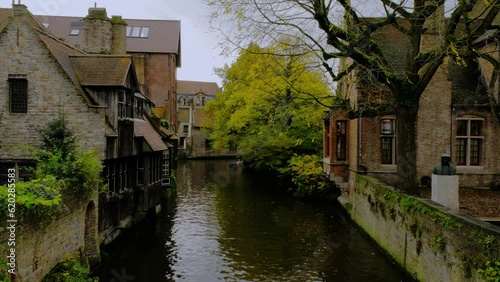 Colorful view from Bonifacius Bridge to old brick mansions with wooden balconies and two swans, located on Bruges canal (Brugge), Flanders, Belgium photo