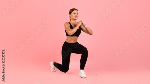 Sporty young female in activewear making lunges exercise in studio