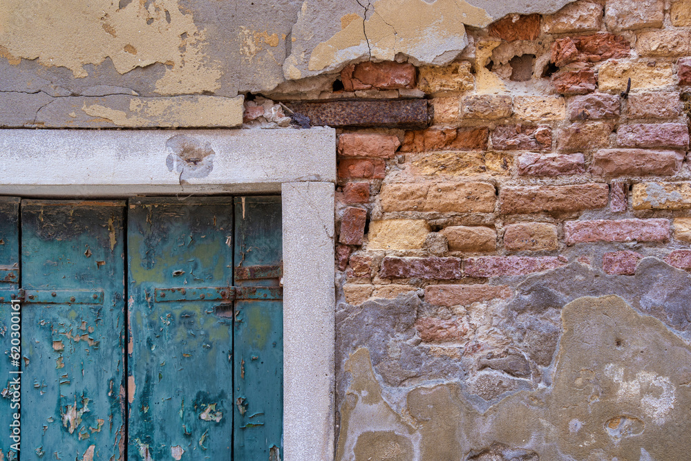 Detail with a green wooden shutter window on a worn out plastered red brick wall, in Venice Italy. Detail with a green wooden shutter window on a worn out plastered red brick wall, in Venice Italy.