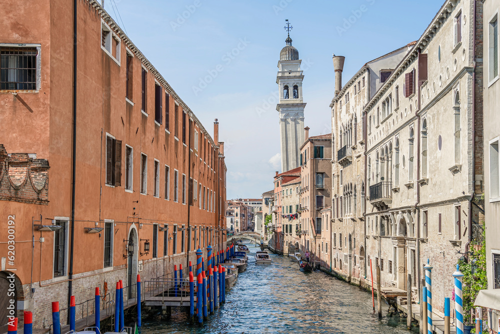 Scenic view from the narrow water canals in Venice with he leaning bell tower (Campanile di San Giorgio dei Greci) of Church of San Giorgio dei Greci
