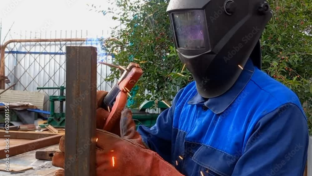 A welder in a protective mask welds a metal , and sparks fly. Industrial construction. Real workflow. work with a thermal electrode, welding of metal parts A welder in a protective mask welds a metal , and sparks fly. Industrial construction. Real workflow. work with a thermal electrode, welding of metal parts