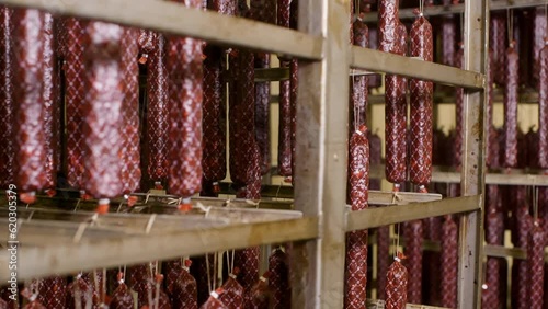 Sausage sticks drying, processing meat products. Smoked sausages maturing on racks at meat production meat factory. Traditional way of ripening sausages on industrial food production plant. 