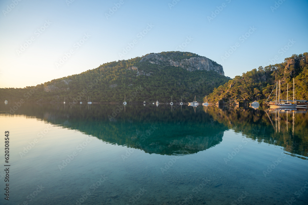 Beautiful sea coast near Cleopatra Bath Bay, Gocek, Fethie, Turkey. Landscape with moor yachts, clear blue water and pine trees in the morning. Beautiful sea coast near Cleopatra Bath Bay, Gocek, Fethie, Turkey. Landscape with moor yachts, clear blue water and pine trees in the morning.