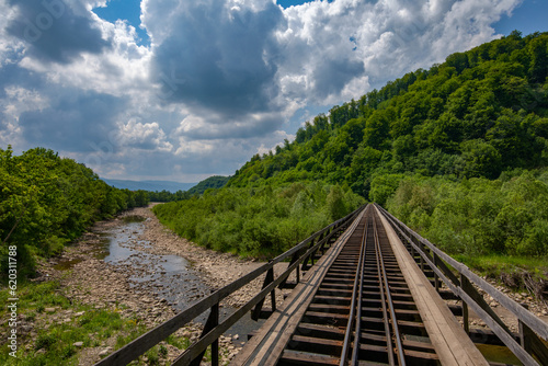 Rustic Serenity: Wooden Railway Bridge Amidst Mountainous Splendor