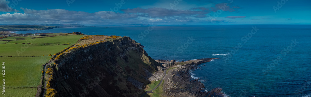 Drone panorama of cliffs and hexagonal stones or pillars at Giants causeway in northern ireland, majestic basalt pillars at the beach on a cloudy day. Wide view of area..