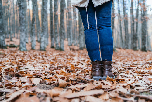 Image of an unrecognizable woman with her feet together on the leaves of the chestnut grove of El Tiemblo, Avila, Spain.