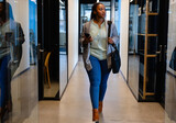 Plus size african american casual businesswoman using smartphone in office corridor