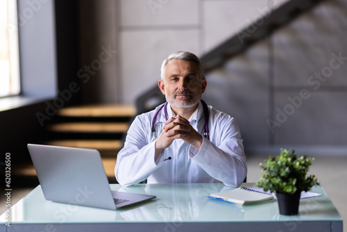 Doctor in hospital office working on laptop at desk