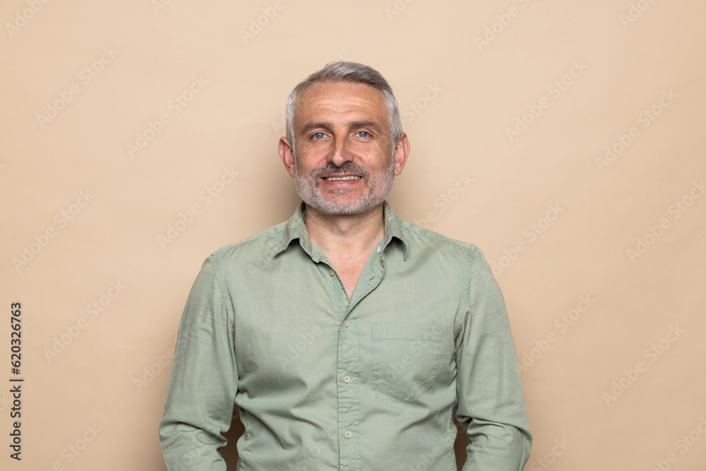 Portrait of nice cheerful content middle aged man copy space isolated over beige pastel color background Portrait of nice cheerful content middle aged man copy space isolated over beige pastel color background