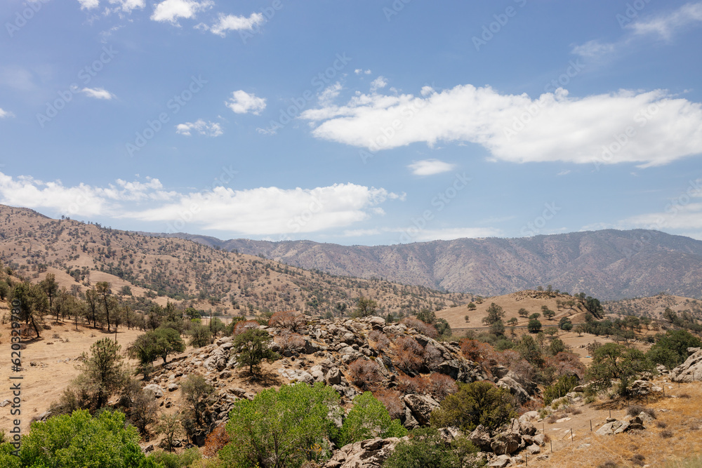 A beautiful American landscape with mountains, trees, and country houses in California on sunny days with blue sky. Bakersfield, California, USA - 7-22-2021