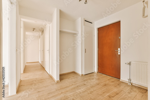 an empty room with white walls and wood flooring, there is a bright red door in the center of the room