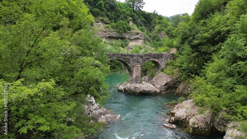 A beautiful turquoise river flows through a dense green forest. Canyon of the Mrtvica river. Montenegro. Danilov bridge. Aerial view. photo