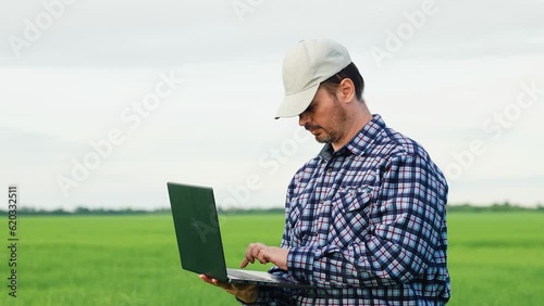 rural worker working farm, agriculture, farming, farm business, man work digital laptop, businessman with laptop his hands inspects field with green wheat, agrotechnics work digital laptop, business photo
