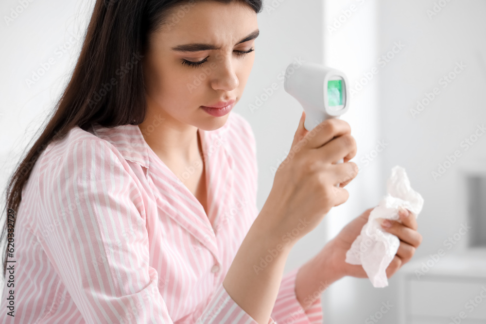 Sick young woman measuring temperature at home Sick young woman measuring temperature at home