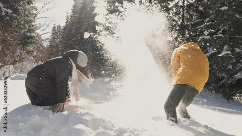 A man and a woman, rejoicing in snow, play in snowballs, throw snow at each other. The couple's love is revealed in video, emphasizing importance nature and happy moments together. Crazy fun in snow