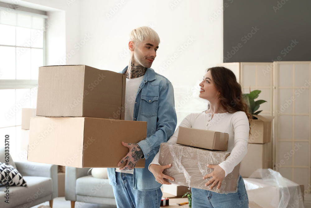 Young couple with cardboard boxes in room on moving day