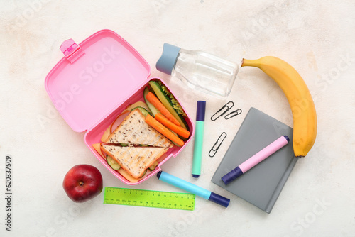 Stationery, drink and lunch box with tasty food on grunge light background