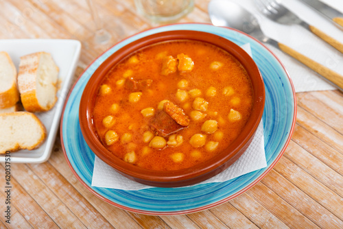 Portion of a traditional dish Spanish cuisine of Garbanzos a la riojana in a ceramic bowl. Served with bread photo