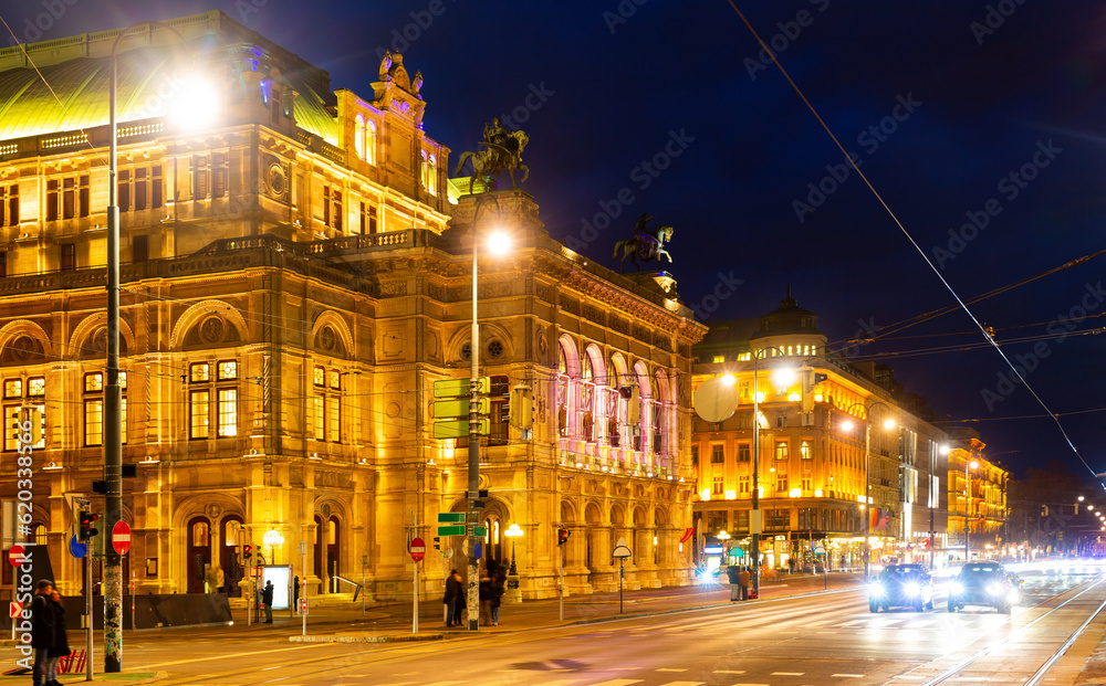 Scenic view of busy night central avenue of Vienna and impressive illuminated building of famous State Opera in winter, Austria.