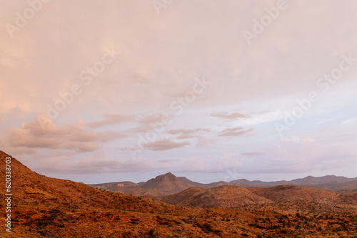A beautiful asphalt road among hills with dry grass. A scenic landscape with highway, mountains on background and blue sky with fluffy clouds on sunny day. Phoenix, AZ, USA - 7-22-2021