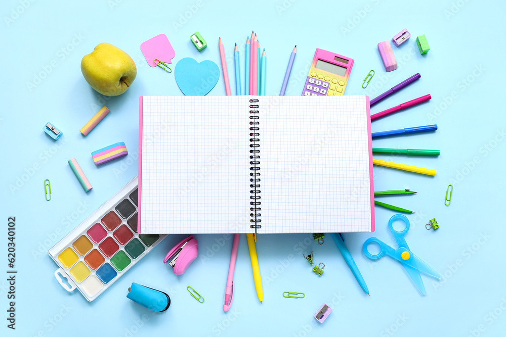 Blank notebook with apple and different stationery on blue background Blank notebook with apple and different stationery on blue background