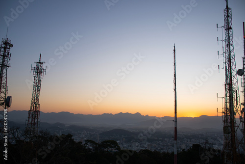 radio and television telecommunication antenna towers with parabolic sunset or sunrise in mountain city in the background photo