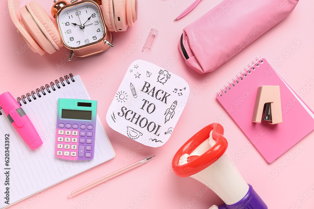 Headphones, alarm clock, megaphone and sheet with text BACK TO SCHOOL on pink background Headphones, alarm clock, megaphone and sheet with text BACK TO SCHOOL on pink background