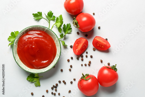 Bowl with tomato paste and fresh vegetables on grey background