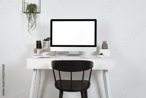 Cozy workspace with computer, houseplants and stationery on wooden desk at home © New Africa