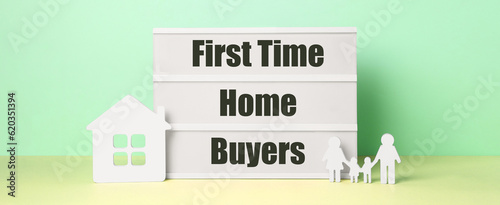 First time home buyers. Lightbox, figures of family and house on table against green wall. Banner design photo