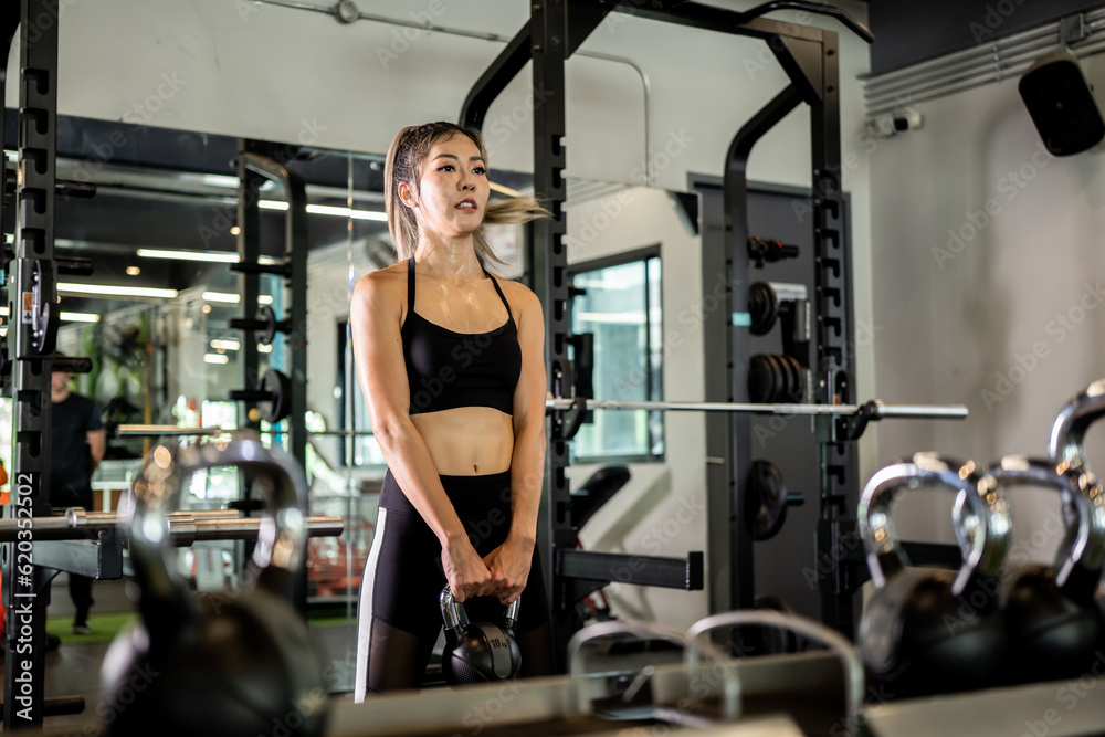 Portrait of a young Asian woman, good-looking, shapely, in a black dress. She's working exercise fitness out in a world-class gym, work hard. Portrait of a young Asian woman, good-looking, shapely, in a black dress. She's working exercise fitness out in a world-class gym, work hard.