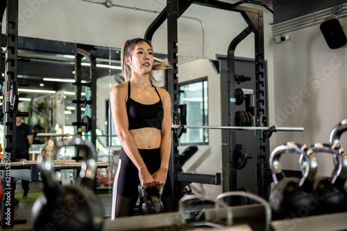 Portrait of a young Asian woman  good-looking  shapely  in a black dress. She s working exercise fitness out in a world-class gym  work hard.