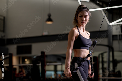 Portrait of a young Asian woman, good-looking, shapely, in a black dress. She's working exercise fitness out in a world-class gym, work hard.